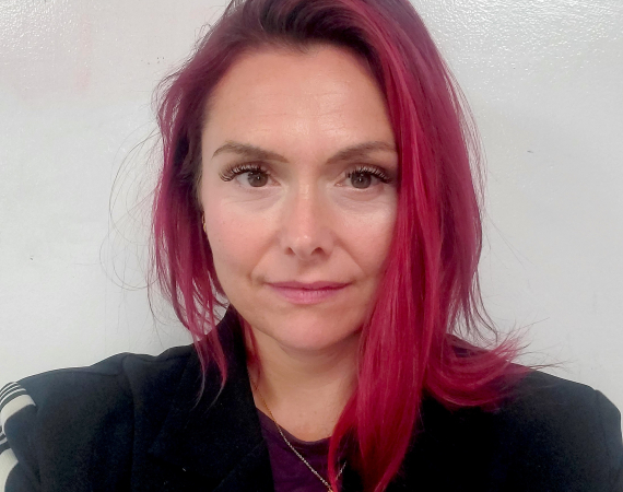 Headshot of Naomi Smyth, a woman with long red hair and a black jacket