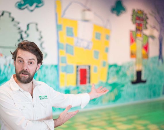 A man gesturing at a colorful mural