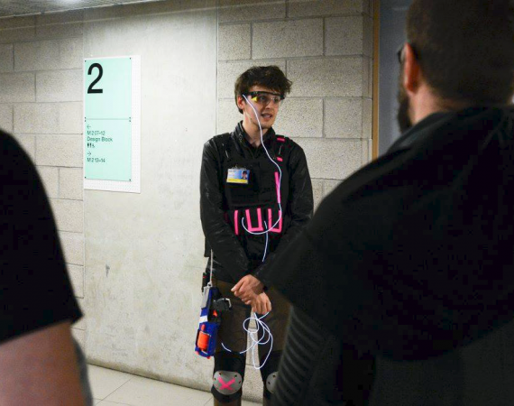 Someone wearing a headset standing in front of a brick wall