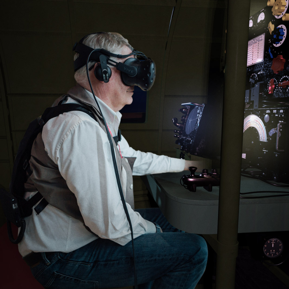 Older gentleman sits in a virtual reality headset during a Dam Busters experience