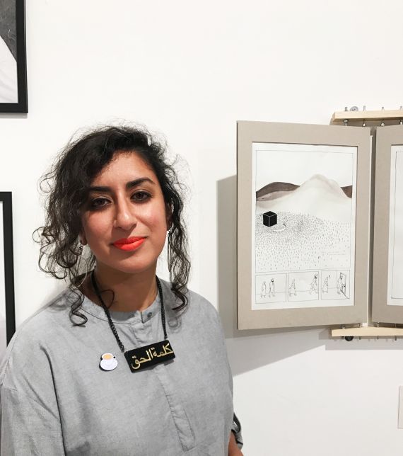 Image of: Sabba Khan, wearing a grey shirt -standing next to an image from her graphic novel