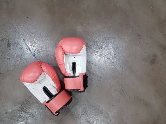 Image of a pair of red and white boxing gloves on a wooden floor