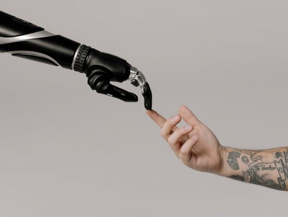 An image of two arms, one robotic, one not, touching fingertips