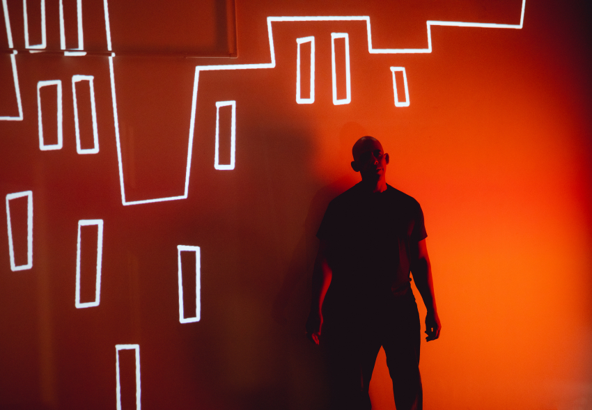 Man standing in front of an illustration city skyline projected on the wall