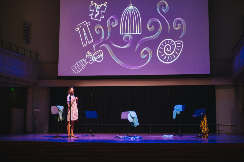 Performer on stage with drawings projected on a screen above