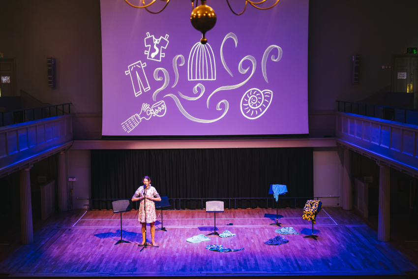 Performer on stage with drawings projected on a screen above